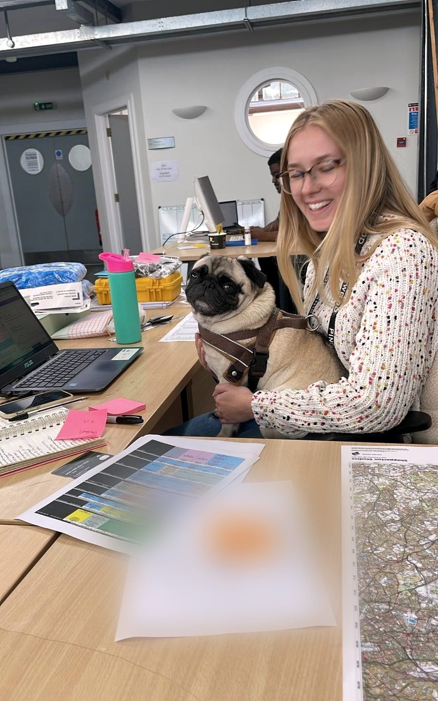 Beth at her desk in the production office, pug on her lap